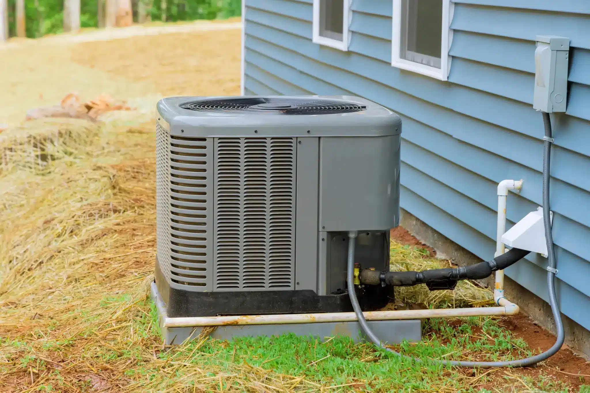 Technician diagnosing failed air conditioner during hot afternoon at Hall County home