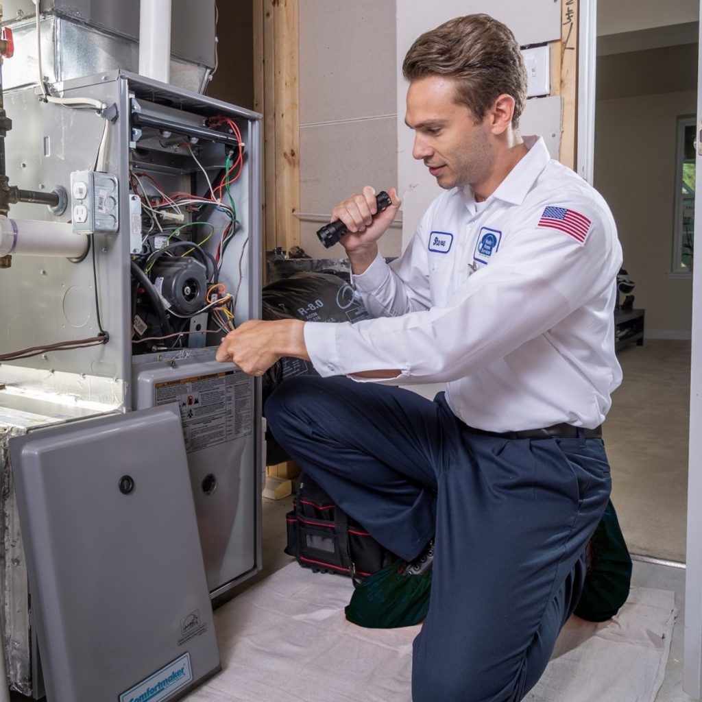 Experienced HVAC technician testing furnace components with diagnostic meter and tools